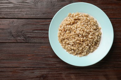 Photo of Delicious pearl barley on wooden table, top view. Space for text