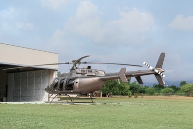 Beautiful helicopter on helipad in field near hangar
