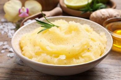 Body scrub with rosemary in bowl on wooden table, closeup