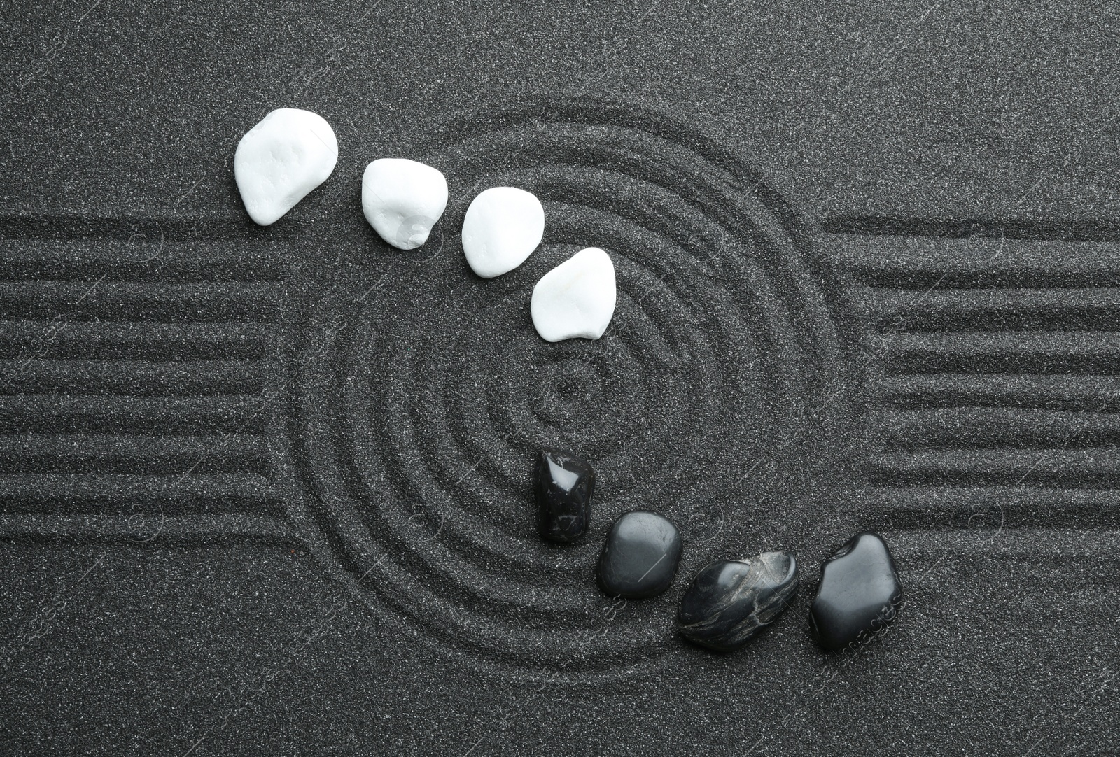 Photo of Stones on black sand with beautiful pattern, flat lay. Zen and harmony