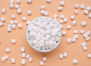 Bowl with sweet marshmallows on orange background, flat lay