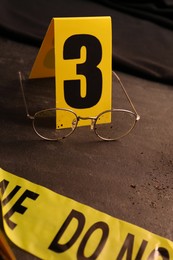 Photo of Crime scene marker and glasses on black slate table