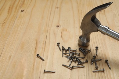 New hammer and metal nails on wooden table. Space for text