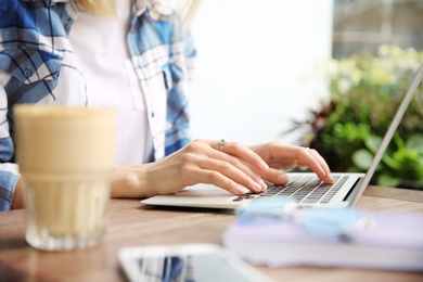 Photo of Young woman working with laptop at desk, closeup
