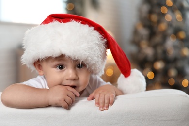 Image of Cute little baby wearing Santa hat at home. Christmas celebration