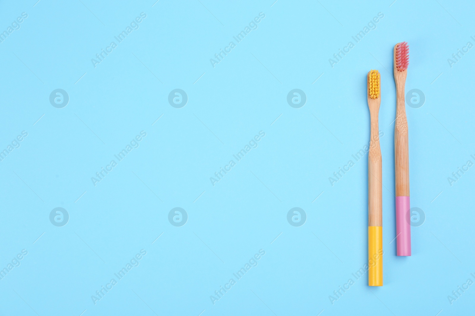 Photo of Toothbrushes made of bamboo on light blue background, flat lay. Space for text