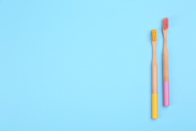 Photo of Toothbrushes made of bamboo on light blue background, flat lay. Space for text