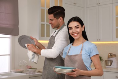 Photo of Happy couple with clean dishes in kitchen