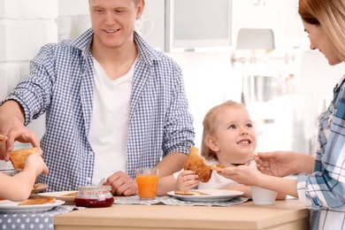 Photo of Parents and cute little children having breakfast with tasty toasted bread at table