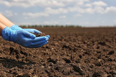 Woman holding pile of soil outdoors, closeup. Space for text