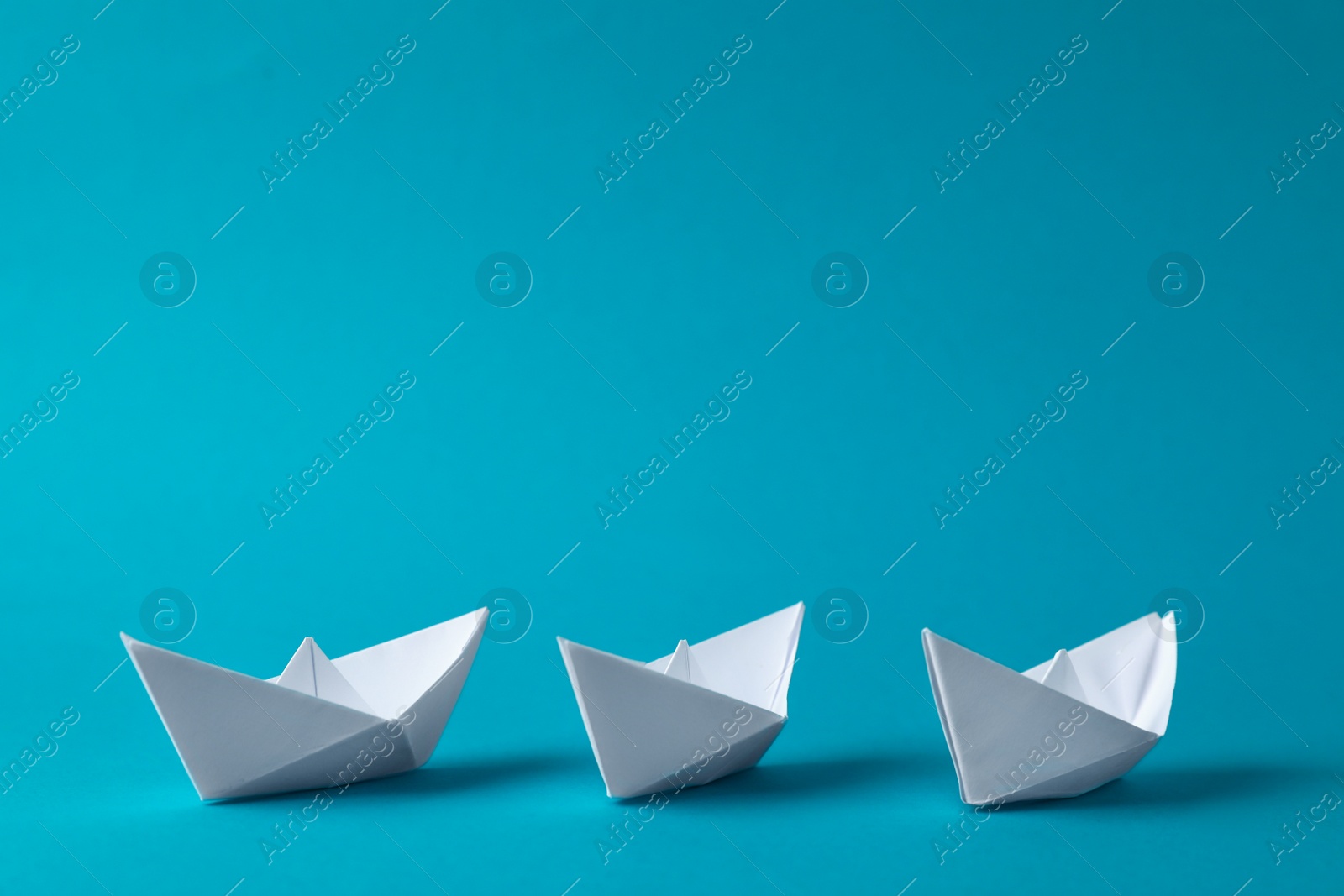 Photo of Handmade white paper boats on light blue background. Space for text