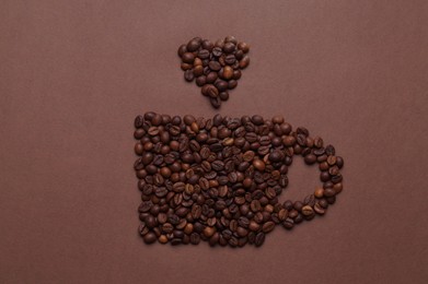 Photo of Cup made of coffee beans on brown background, top view
