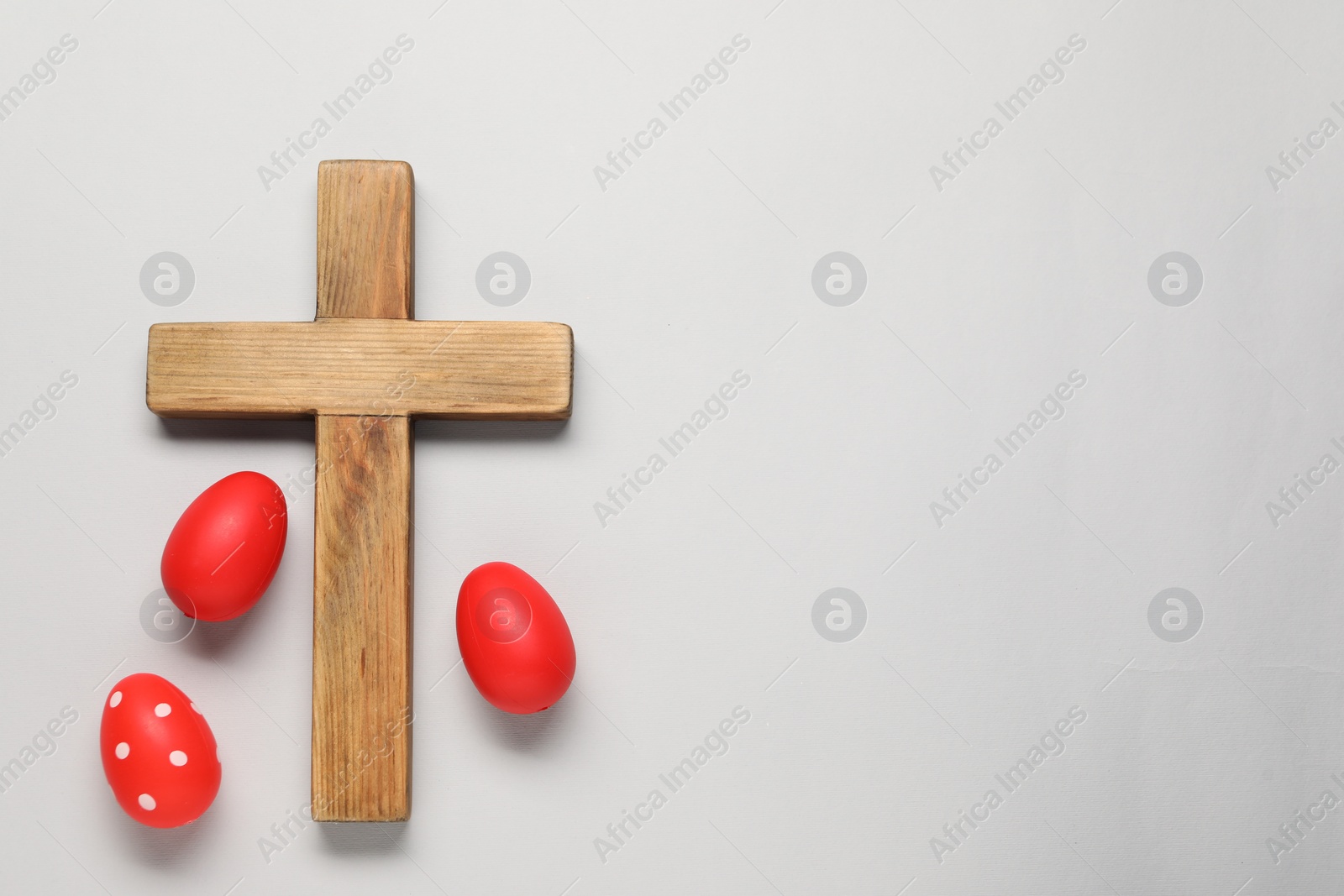 Photo of Wooden cross and painted Easter eggs on light grey background, flat lay. Space for text