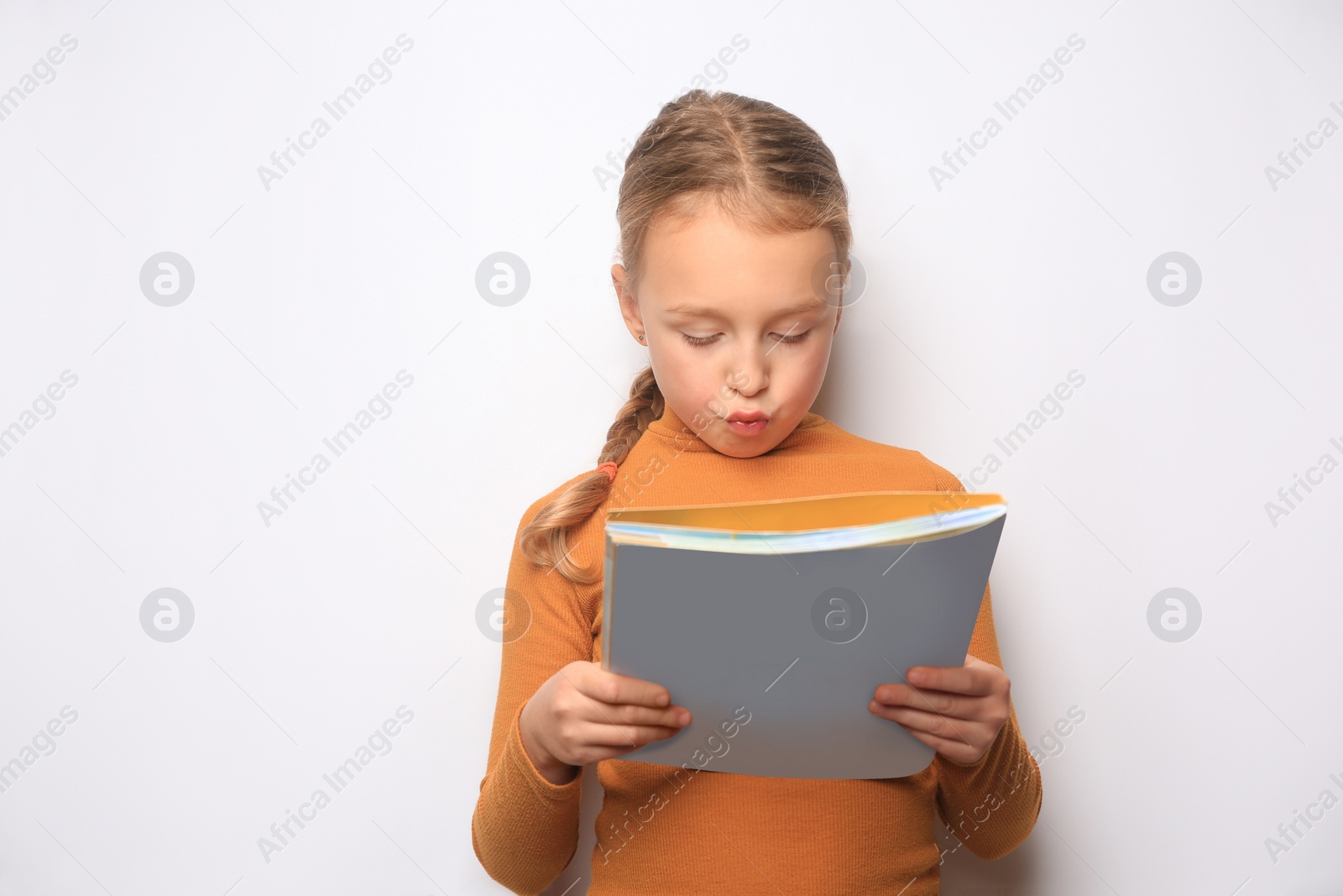 Photo of Emotional little girl reading book on white background. Space for text