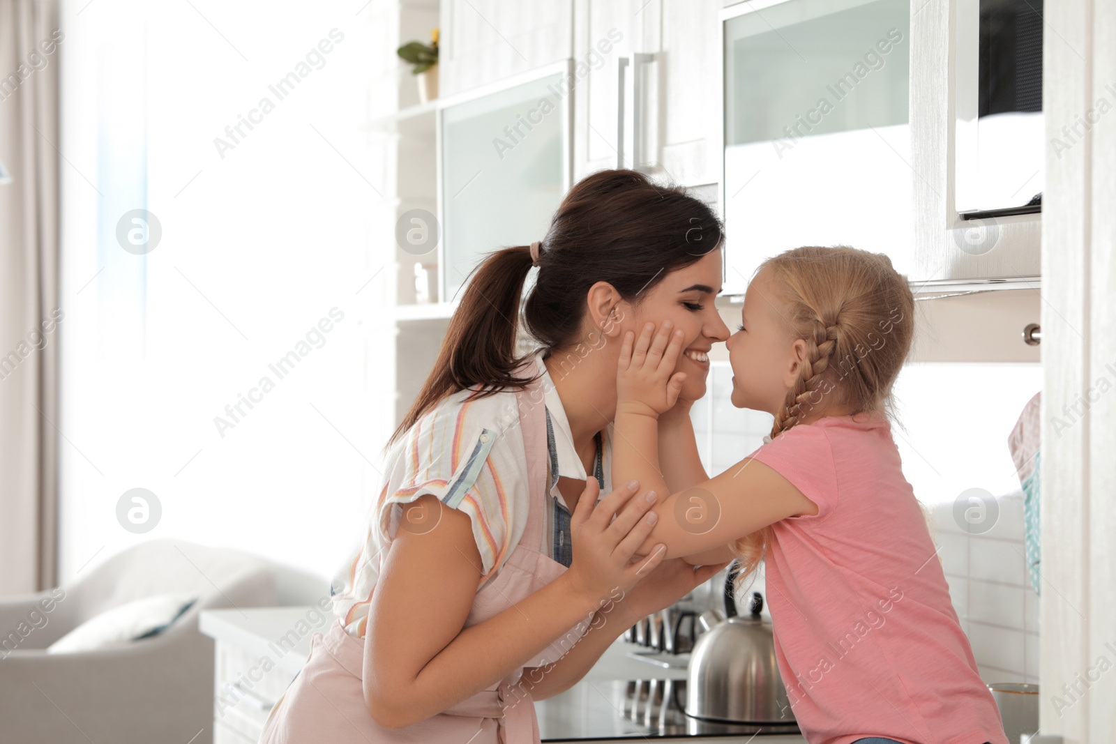 Photo of Young beautiful woman and her daughter having fun in kitchen
