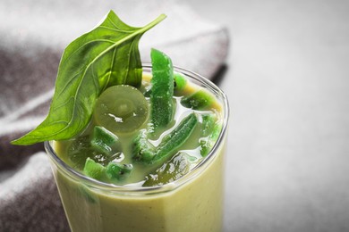 Photo of Glass of delicious smoothie with grape, candied kiwi and basil on grey table, closeup. Space for text