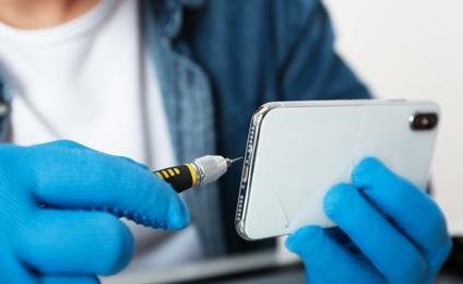 Technician repairing broken smartphone, closeup of hands