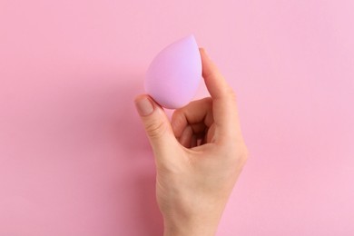 Photo of Woman with makeup sponge on pink background, top view