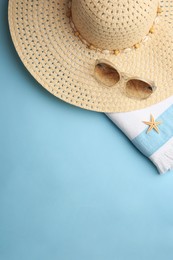Flat lay composition with beach accessories on light blue background, space for text