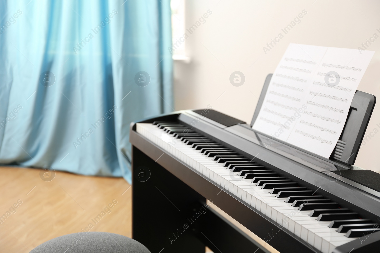 Photo of Modern piano with music sheets in room