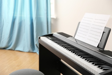 Modern piano with music sheets in room