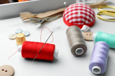Photo of Threads and other sewing supplies on white marble table