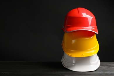 Photo of Stack of hard hats and space for text on black background. Safety equipment