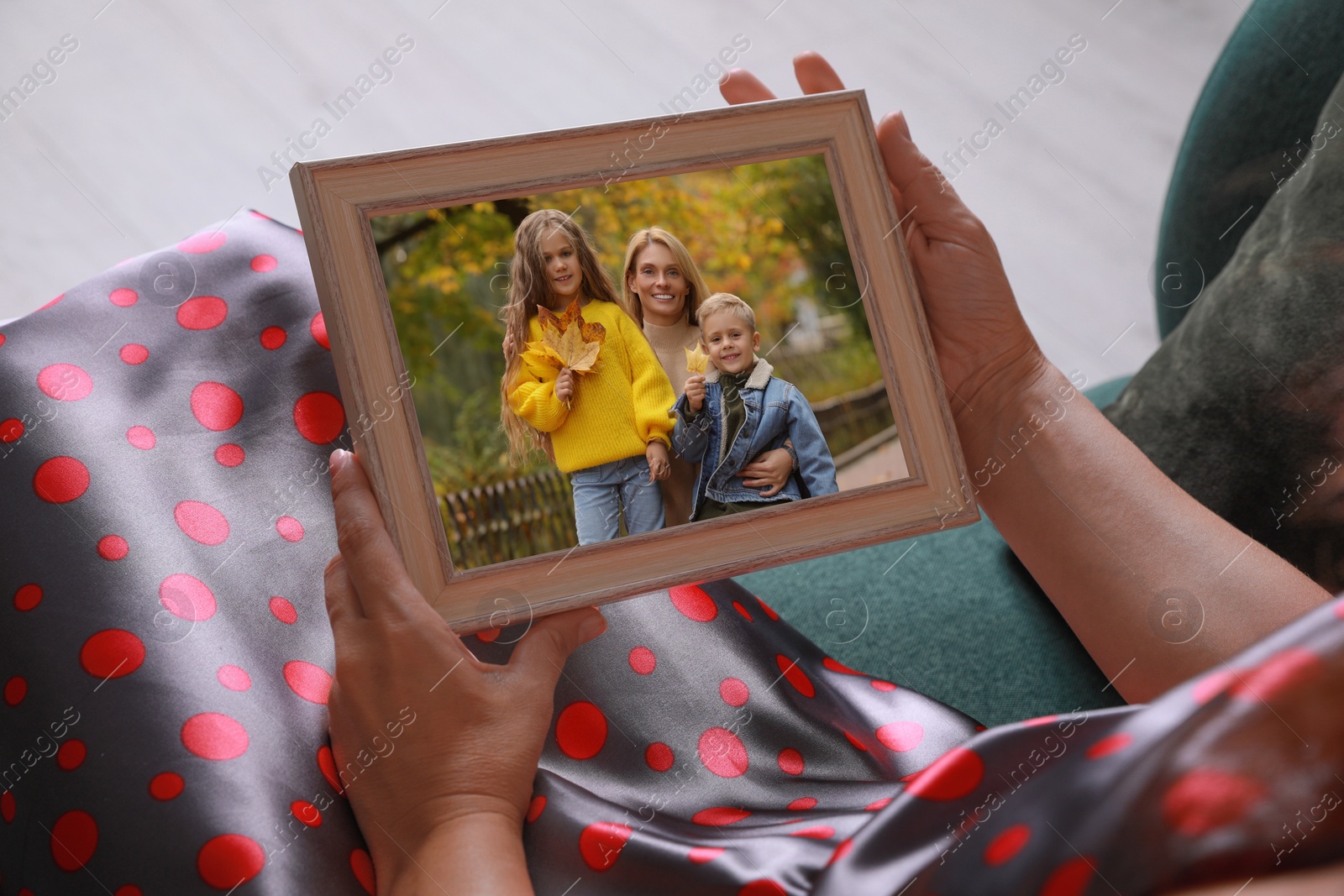 Image of Woman holding frame with photo portrait of her family indoors, closeup