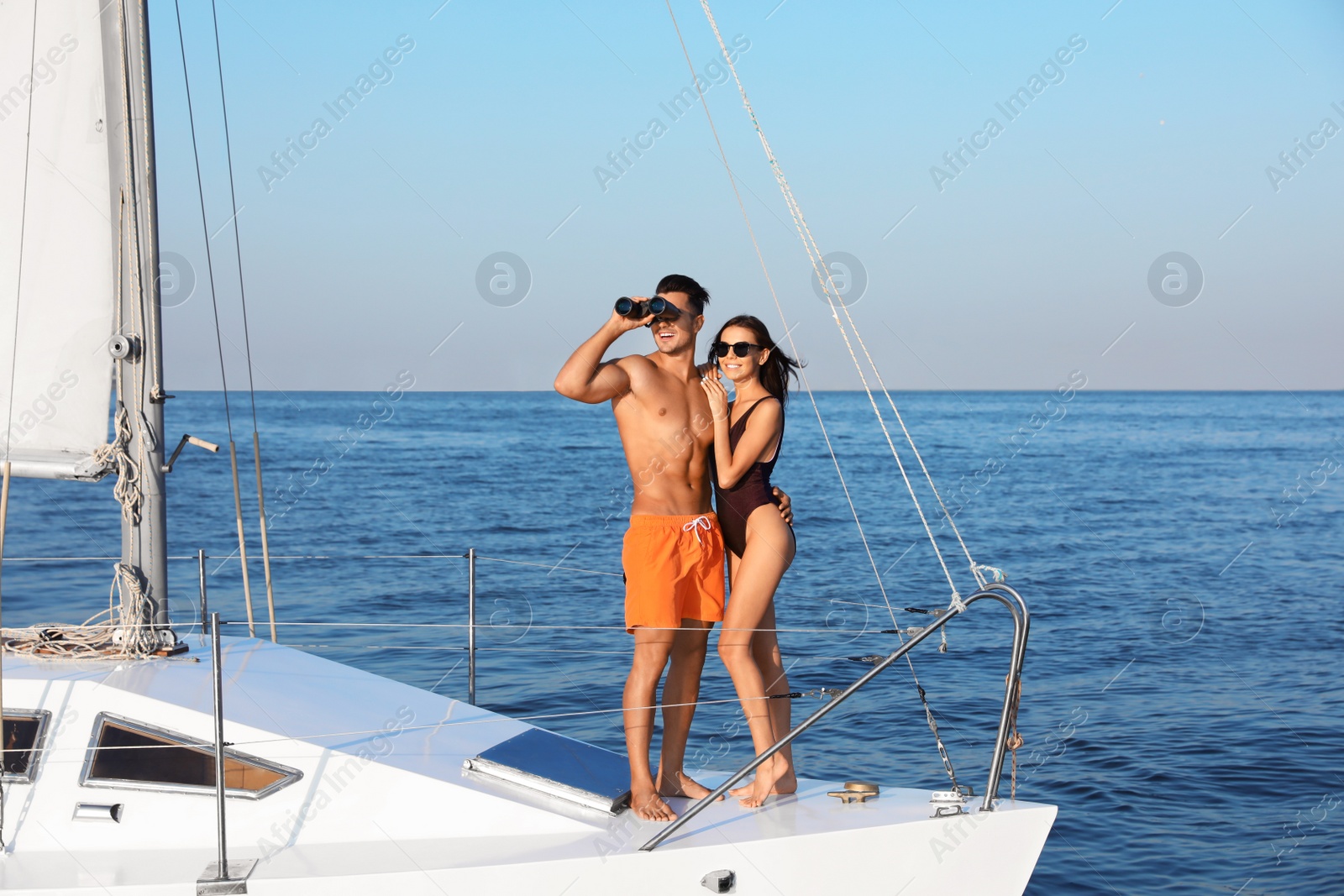 Photo of Young man and his beautiful girlfriend in bikini on yacht. Happy couple during sea trip