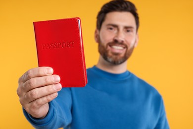 Photo of Immigration. Happy man with passport on orange background, selective focus