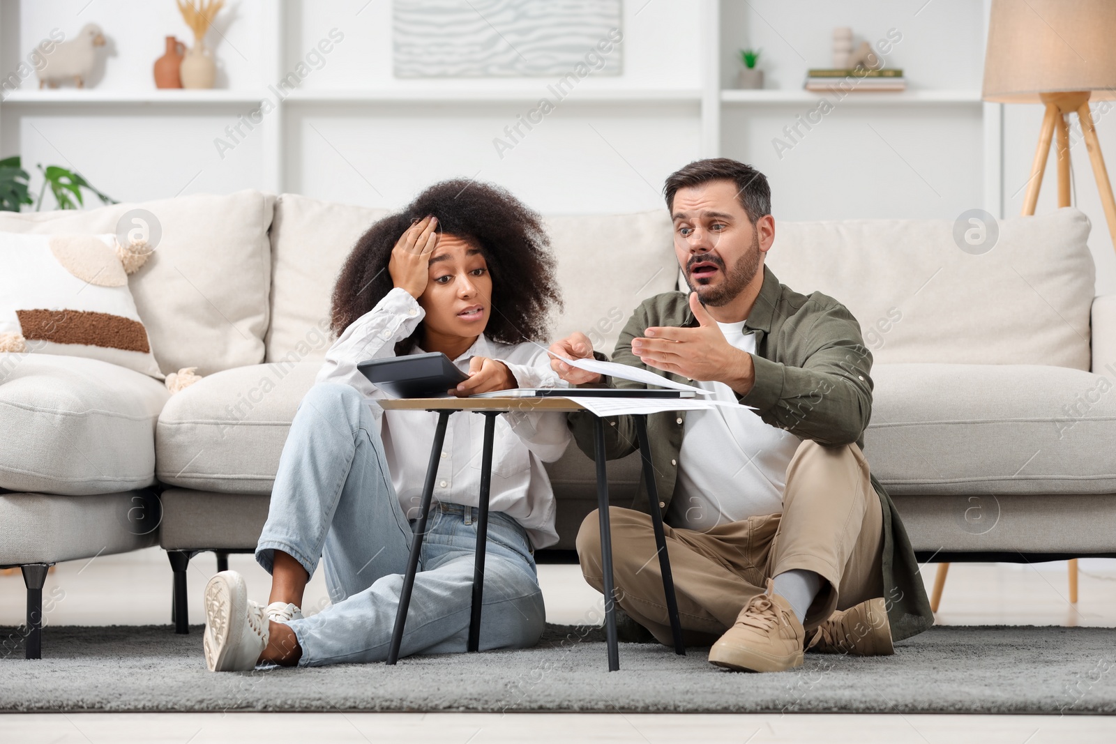 Photo of Shocked couple with calculator and debt notification planning budget at home. Financial problem