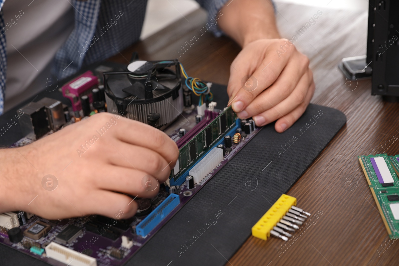 Photo of Male technician repairing motherboard at table, closeup