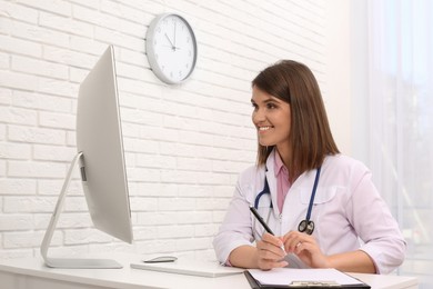 Photo of Pediatrician consulting patient online at table in clinic