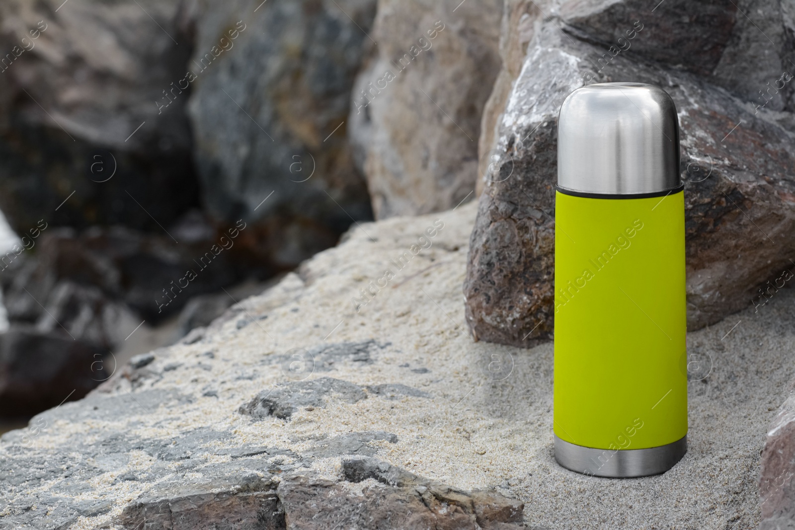 Photo of Metallic thermos with hot drink on stone, space for text