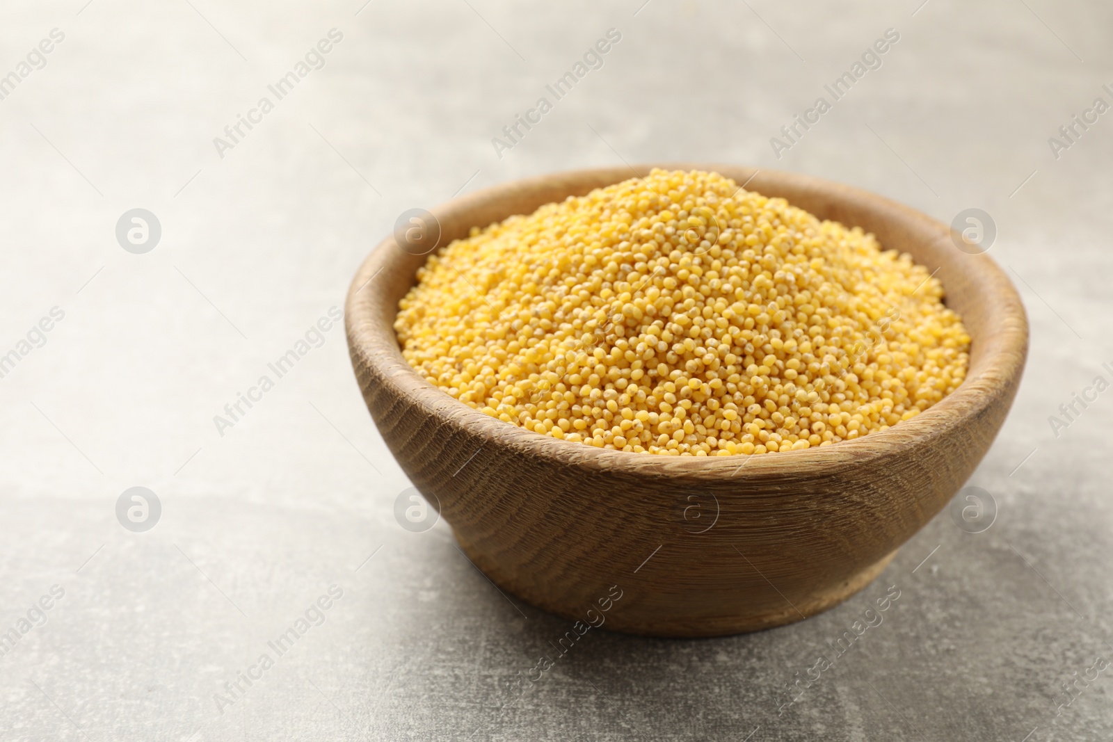 Photo of Millet groats in bowl on light grey table, space for text