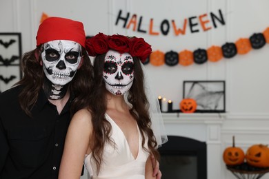 Photo of Couple in scary bride and pirate costumes indoors, space for text. Halloween celebration