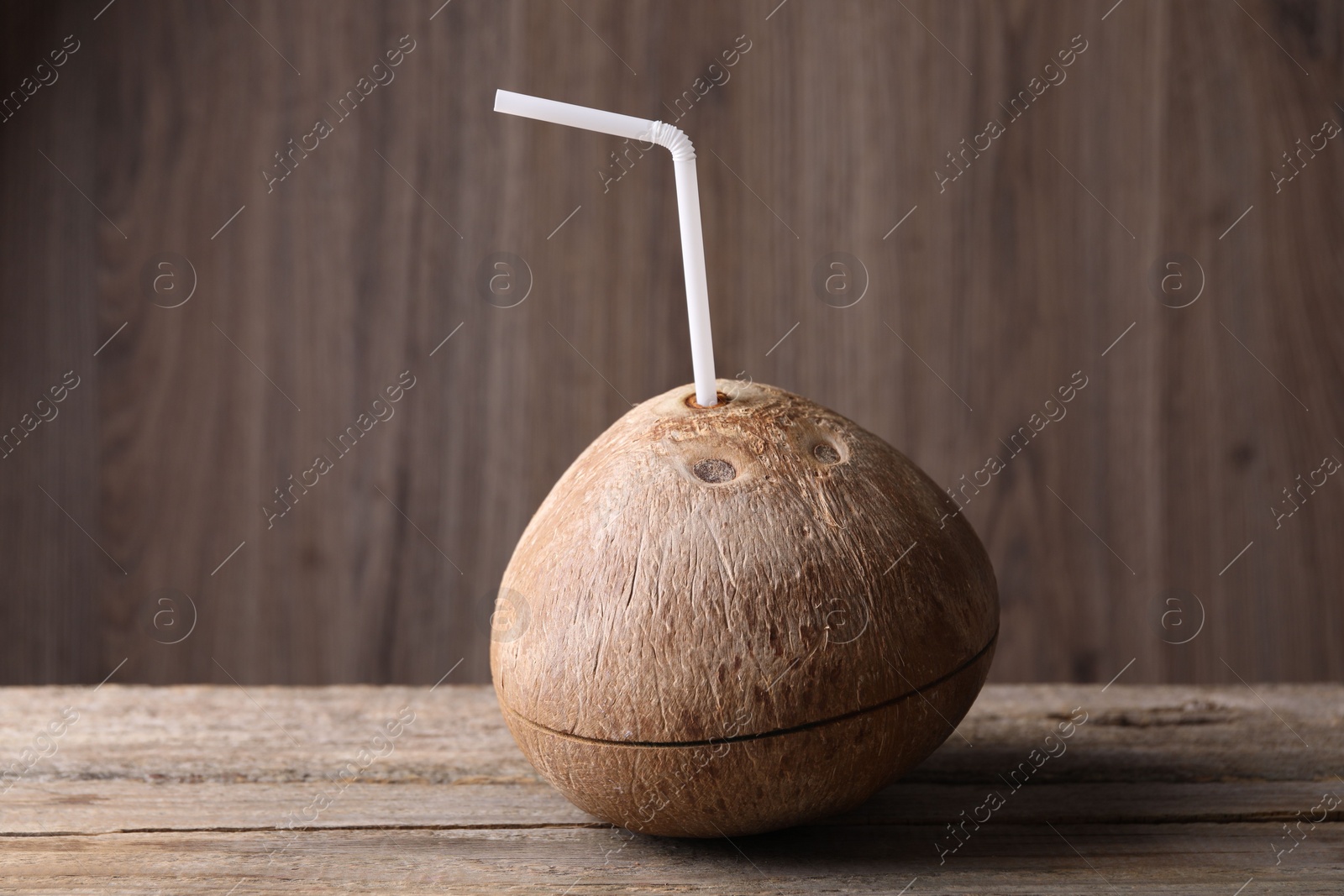 Photo of Coconut water. Fresh nut with straw on wooden table