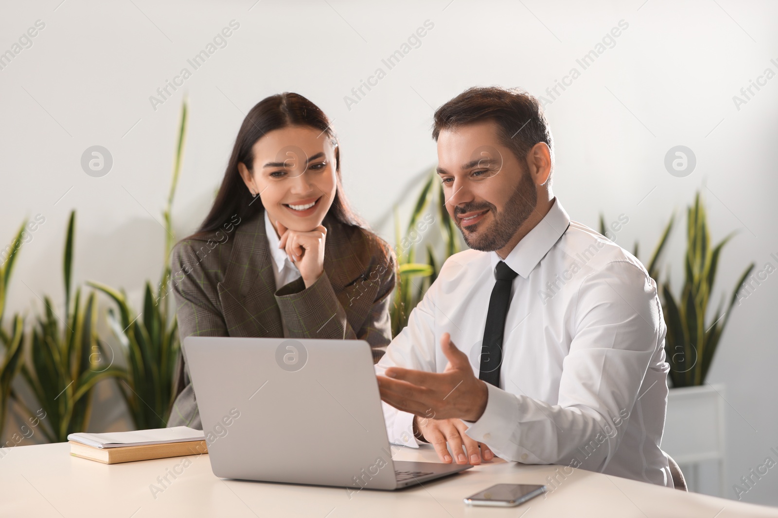 Photo of Colleagues working on laptop at desk in office