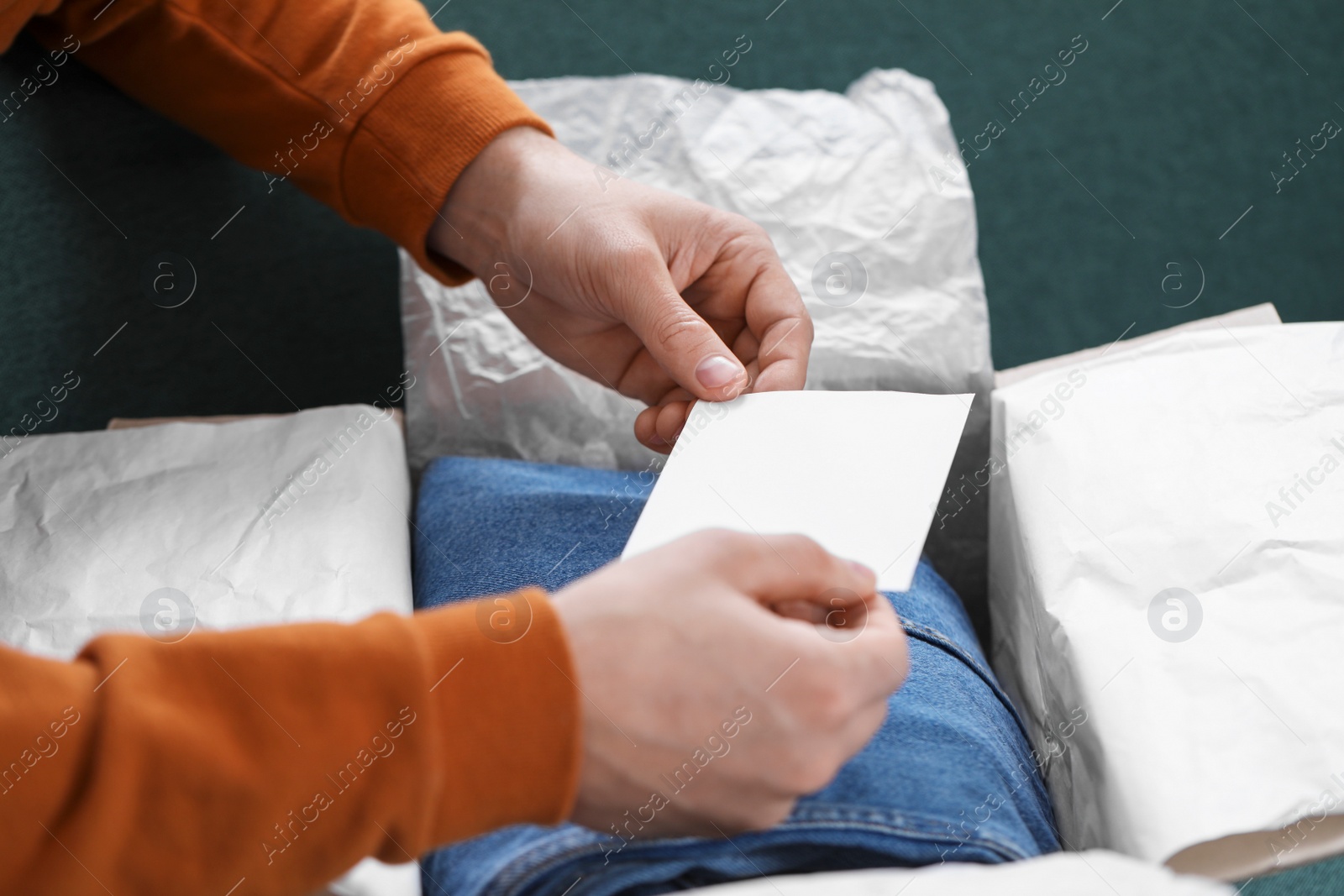 Photo of Man holding greeting card near parcel with Christmas gift, closeup