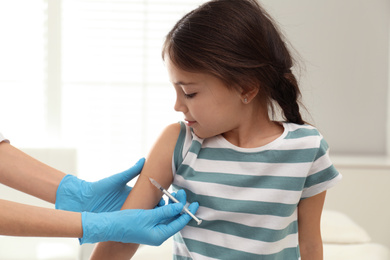 Photo of Doctor vaccinating little child in modern clinic