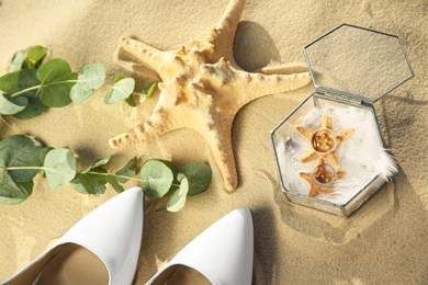 Photo of Composition with gold wedding rings on sandy beach