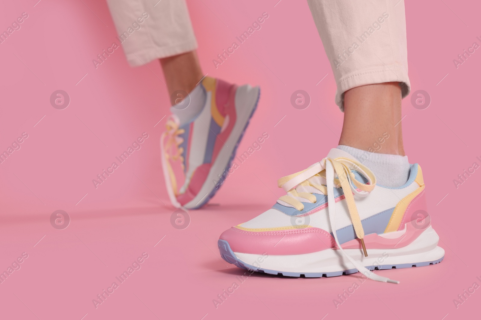 Photo of Woman wearing new stylish sneakers on pink background, closeup. Space for text