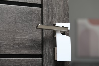 Photo of Wooden door with blank hanger on metal handle, closeup