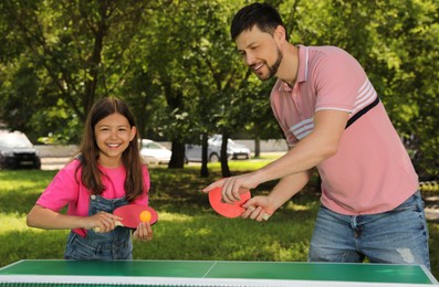 Happy man with his daughter playing ping pong in park
