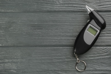 Photo of Modern breathalyzer on grey wooden background, top view. Space for text