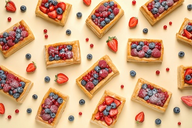 Fresh delicious puff pastry with sweet berries on beige background, flat lay