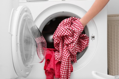 Photo of Housewife putting clothes into washing machine