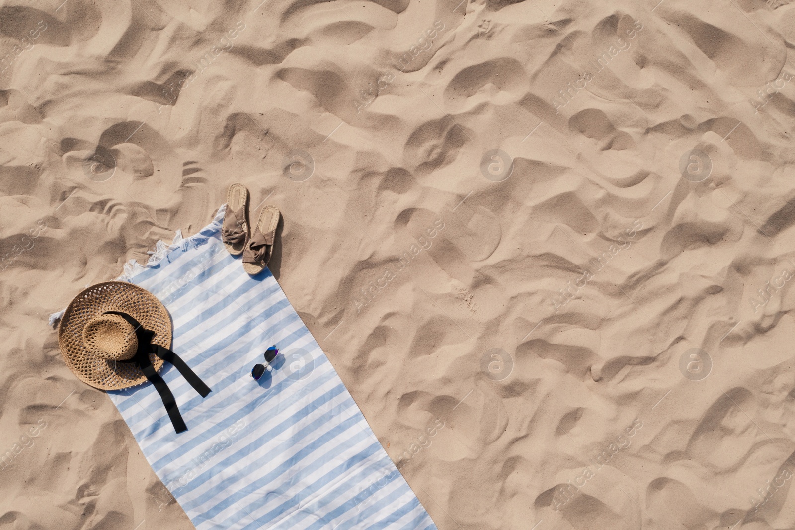 Towel with beach accessories on sand, top view. Space for text Image of Towel with beach accessories on sand, top view. Space for text
