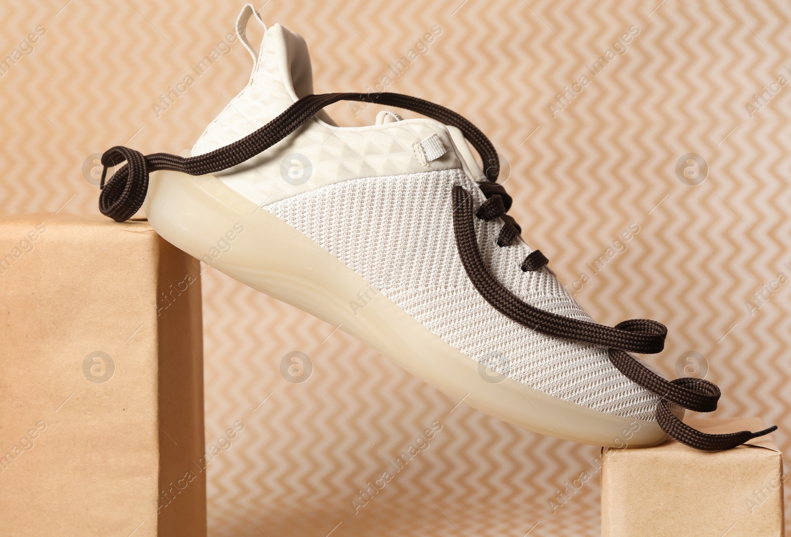 Photo of Stylish shoe with brown laces against beige background