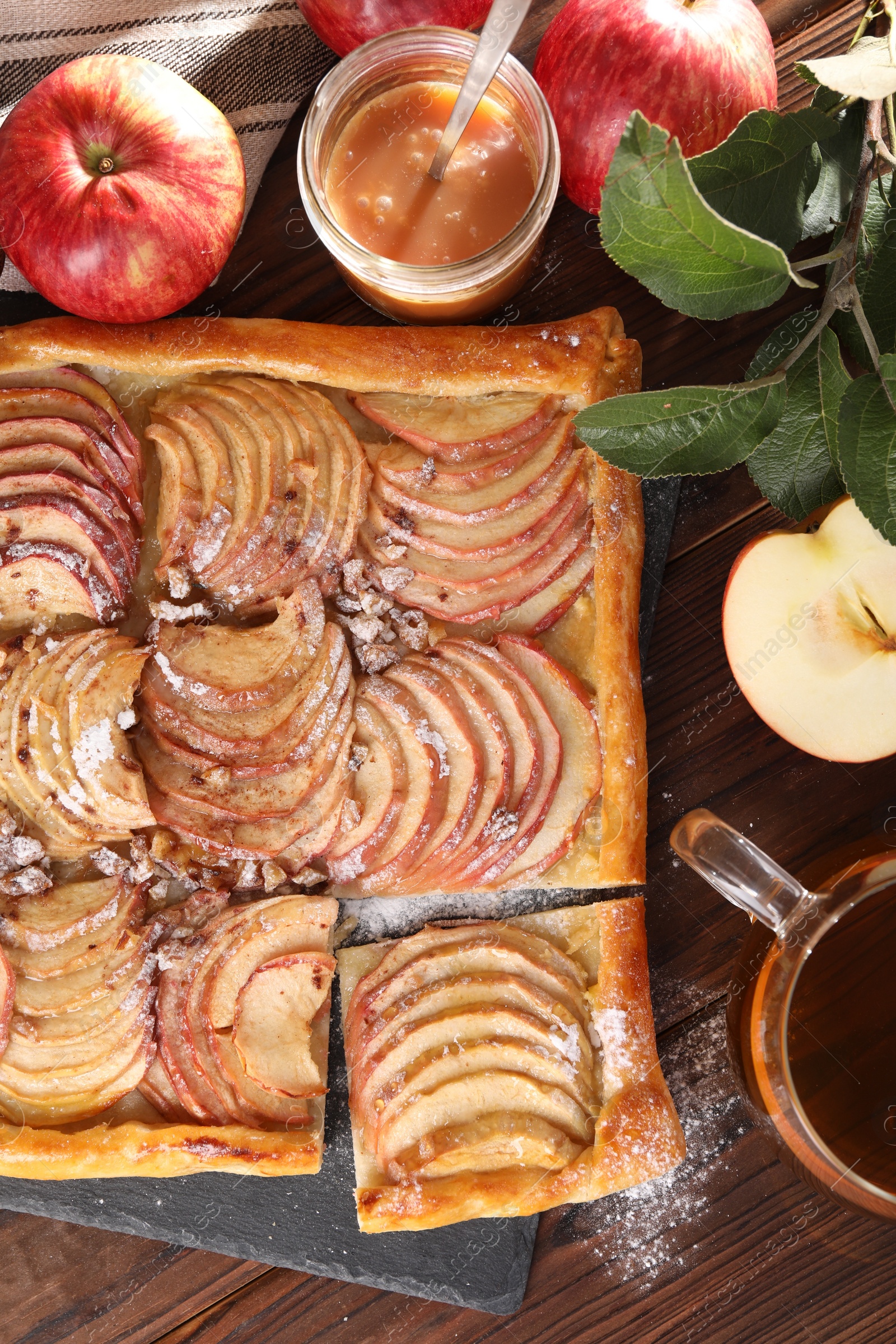 Photo of Freshly baked apple pie served with tea on wooden table, flat lay